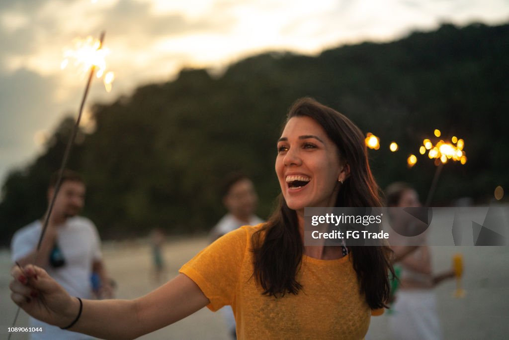 Woman celebrating the new year on the beach with sparkler