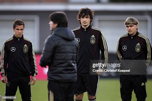 Mario Goetze , Mats Hummels and Marcel Schmelzer watch at national coach Joachim Loew during the DFB training session at the training ground of the...