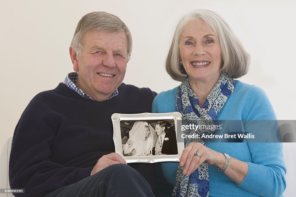 Senior couple holding a framed wedding photogh