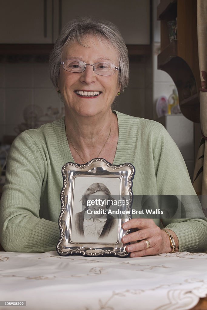 Senior woman with photograph of herself as a girl