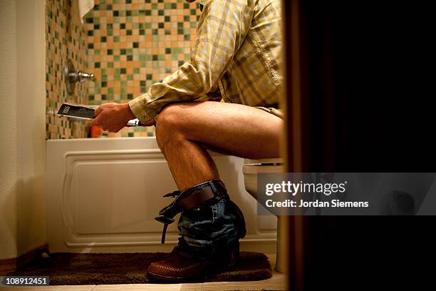male reading magazine on toilet. - men taking a dump stockfoto's en -beelden