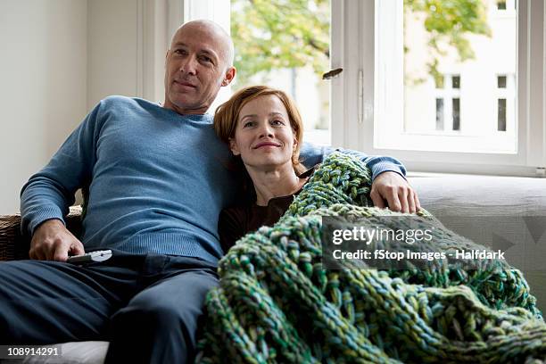 a mature couple relaxing on a sofa - mann frau daheim stock-fotos und bilder