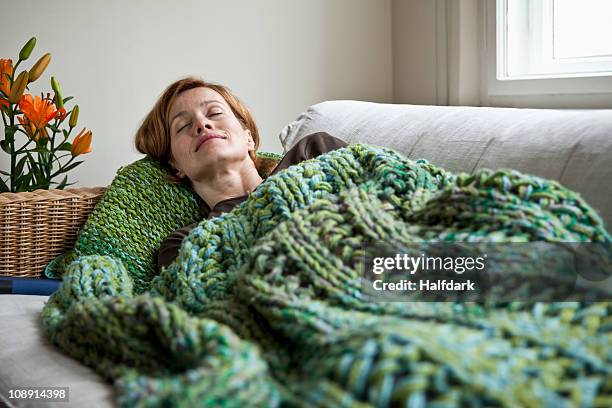 a woman napping on a sofa - cobertor imagens e fotografias de stock