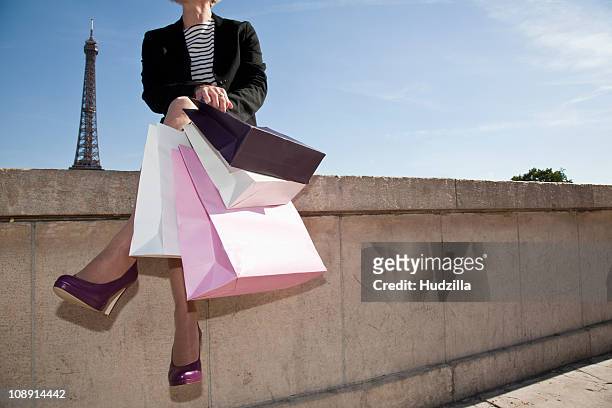 a woman with four shopping bags sitting on a wall  in paris, france - low section stock pictures, royalty-free photos & images