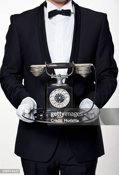 a butler holding an antique rotary phone on a silver tray, midsection - antique phone fotografías e imágenes de stock