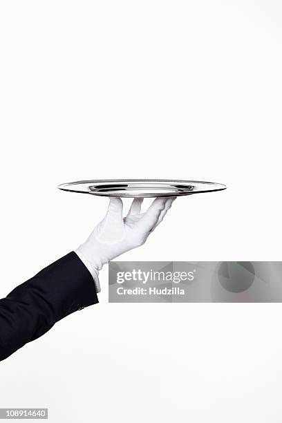 a butler presenting an empty silver tray, focus on hand - zilverkleurige handschoen stockfoto's en -beelden