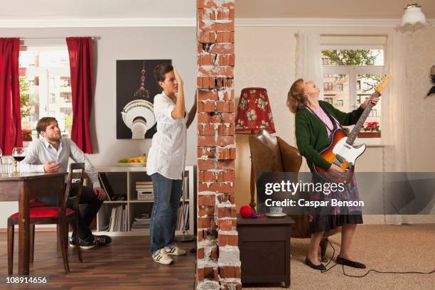 a split screen showing an angry woman pounding on the wall to her neighbor - buren stockfoto's en -beelden