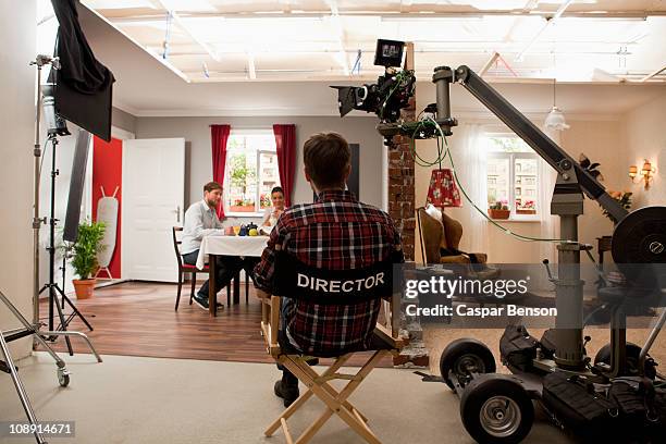 a director on a film set watching actors perform a scene - directors chair fotografías e imágenes de stock