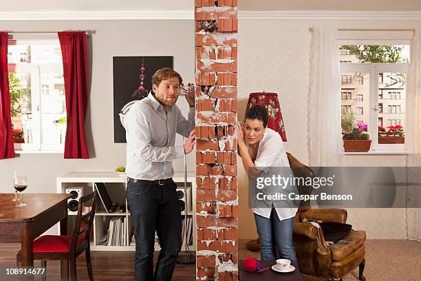 man and woman listening on either side of wall with drinking glasses - eavesdropping stock pictures, royalty-free photos & images