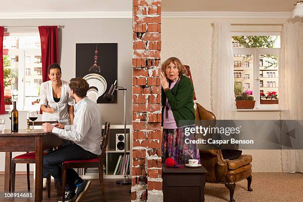 an senior woman listening to her neighbors arguing - tendre l'oreille photos et images de collection