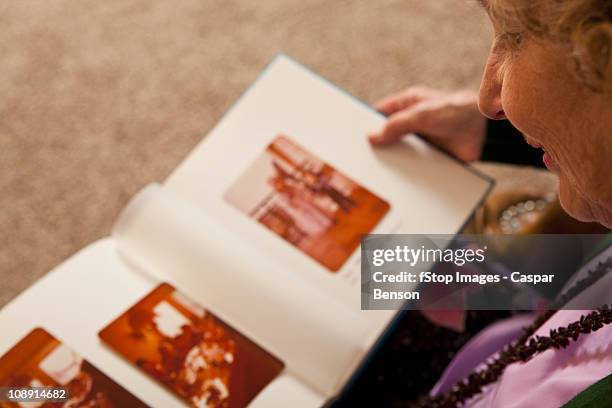 a senior woman looking at a photo album - f 84 stock-fotos und bilder