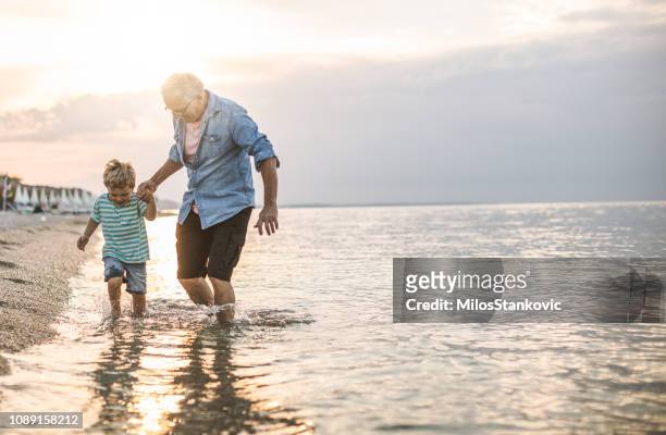 opa en kleinzoon op het strand - active senior man stockfoto's en -beelden