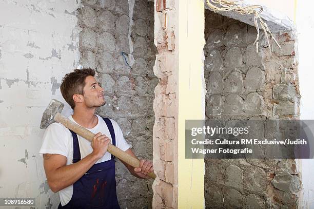 man knocking down wall - sledgehammer stockfoto's en -beelden