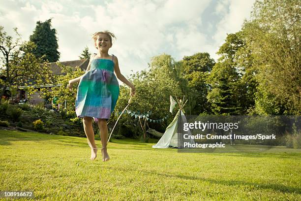 girl skipping in garden - seilspringen stock-fotos und bilder