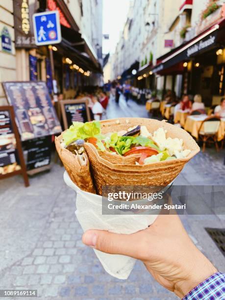 eating french crepe pancake with cheese and fresh vegetables on the street, personal perspective - comida francesa fotografías e imágenes de stock