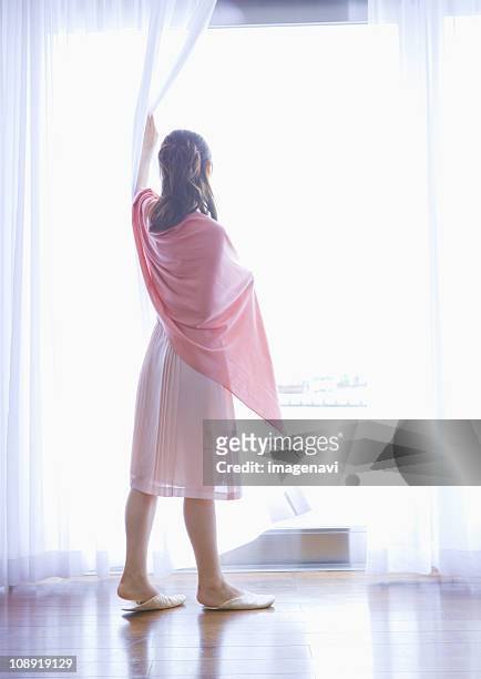 young woman standing by the window - shawl stock pictures, royalty-free photos & images
