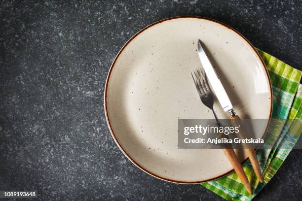 empty plate and fork and knife with napkin on dark grey stone background - vintage silverware stock pictures, royalty-free photos & images
