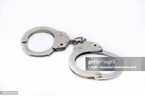 metal handcuffs against white background. - manette foto e immagini stock