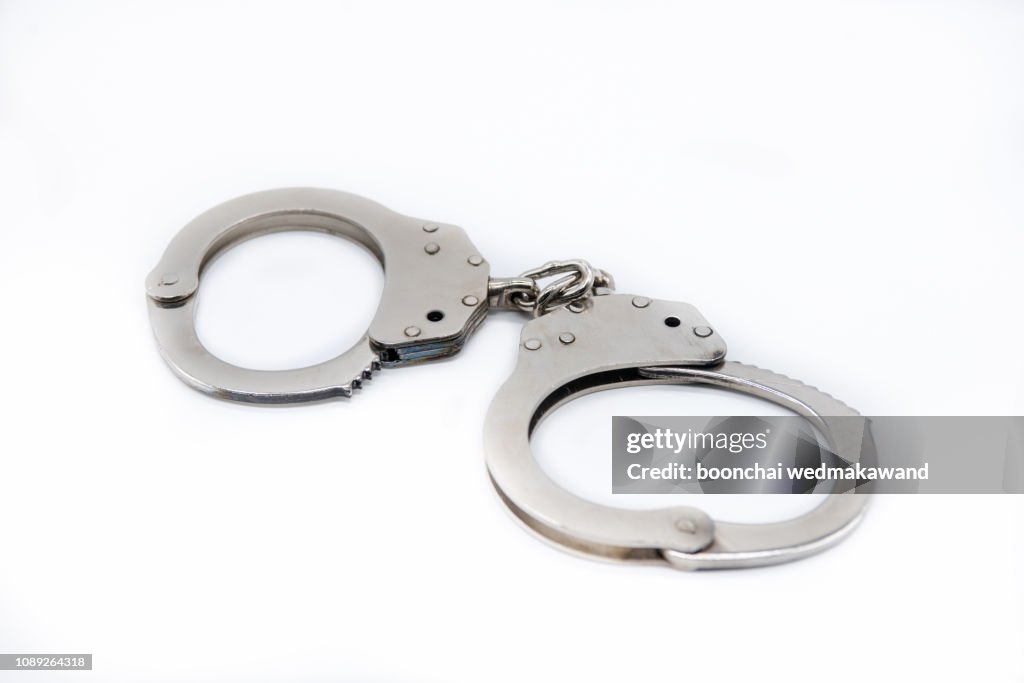 Metal handcuffs against white background.