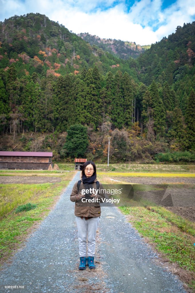 A woman standing at the center of the road at a farmland, Miyama, Kyoto, Japan
