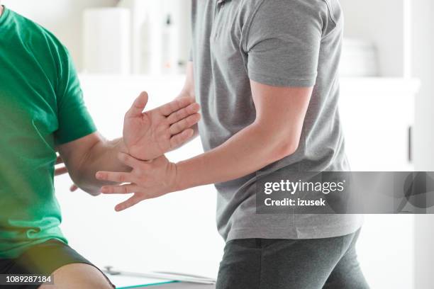 physical therapist examining senior man in rehabilitation center - rheumatism stock pictures, royalty-free photos & images
