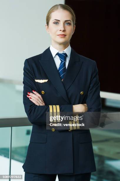 portrait of female pilot standing at airport lobby - airline pilot imagens e fotografias de stock