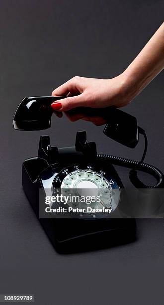 woman's hand lifting telephone receiver - phone receiver stock pictures, royalty-free photos & images