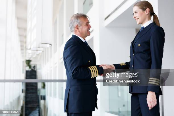 handshaking experienced senior pilot and new woman pilot - airline pilot imagens e fotografias de stock