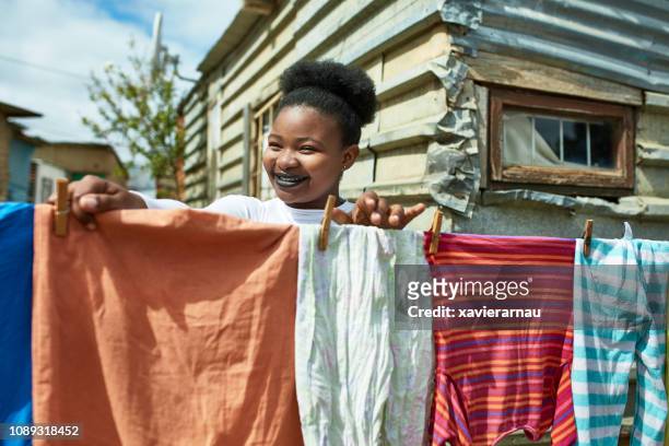 sorrindo de secagem roupa de mulher fora da cabana - township - fotografias e filmes do acervo