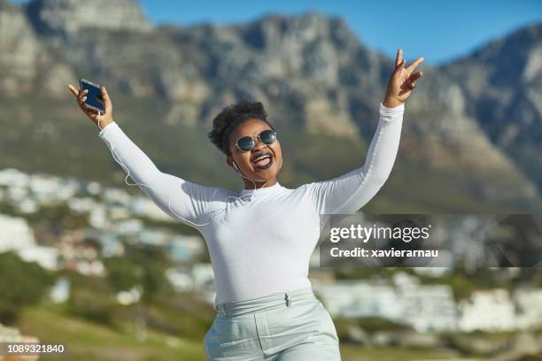 happy young woman dancing while listening music - south african culture stock pictures, royalty-free photos & images