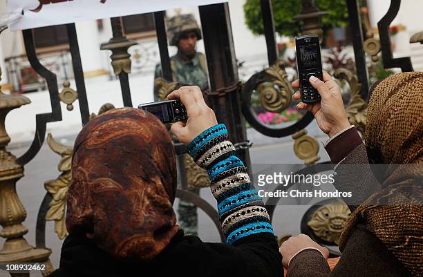 Two protesting women take pictures of an Egyptian Army soldier guarding the Egyptian Parliament building on February 9, 2011 in Cairo, Egypt....