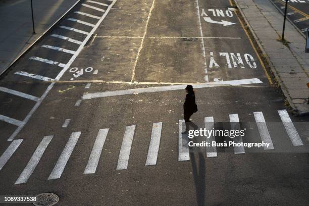 a woman crossing a street in dumbo, brooklyn, new york city, usa - empty city coronavirus stock-fotos und bilder