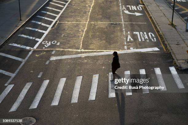 a woman crossing a street in dumbo, brooklyn, new york city, usa - empty city coronavirus fotografías e imágenes de stock