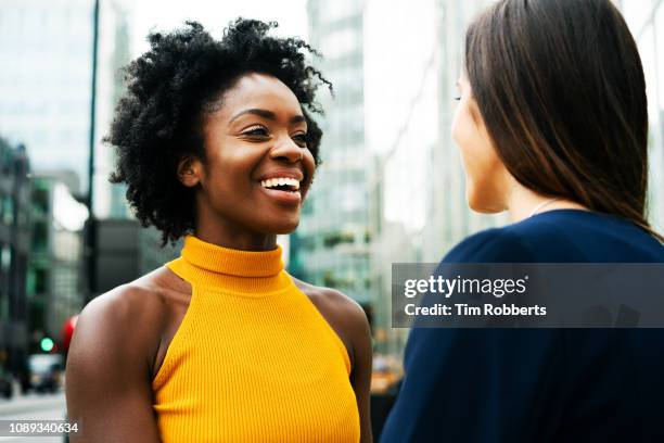 two women talking and smiling in city - two women talking stockfoto's en -beelden