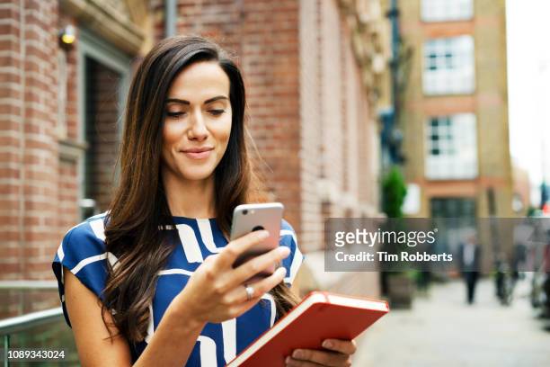 woman using smart phone on street - friendly business phonecall stockfoto's en -beelden