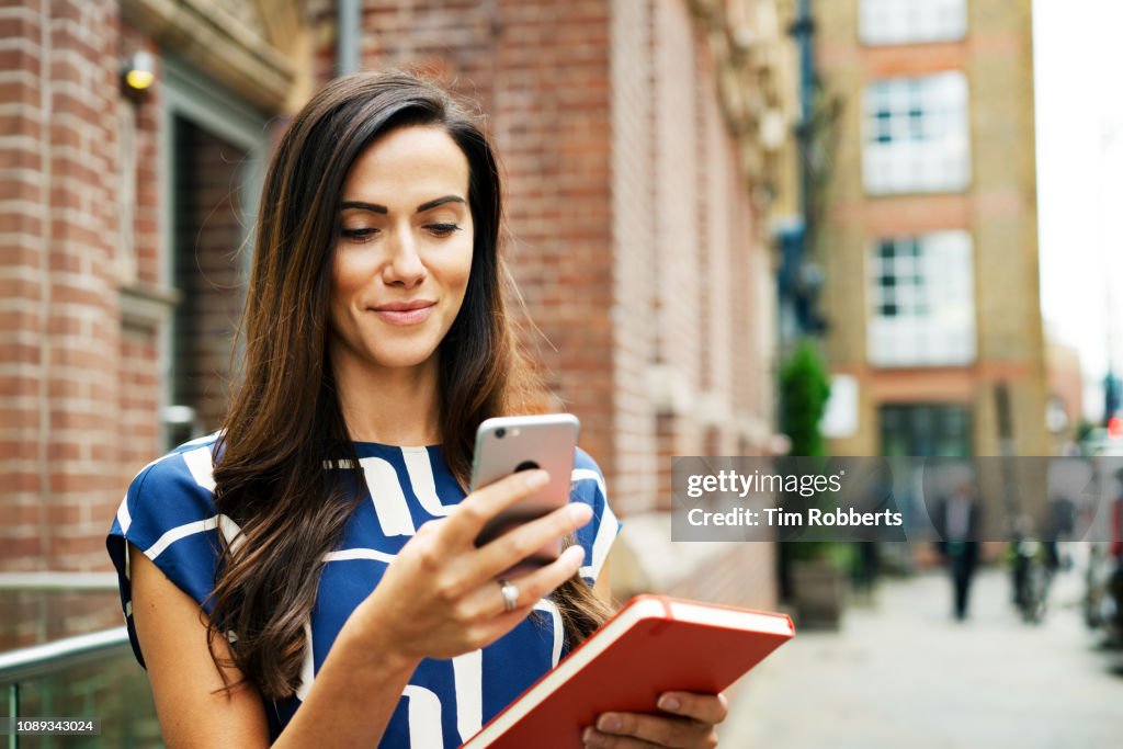 Woman using smart phone on street