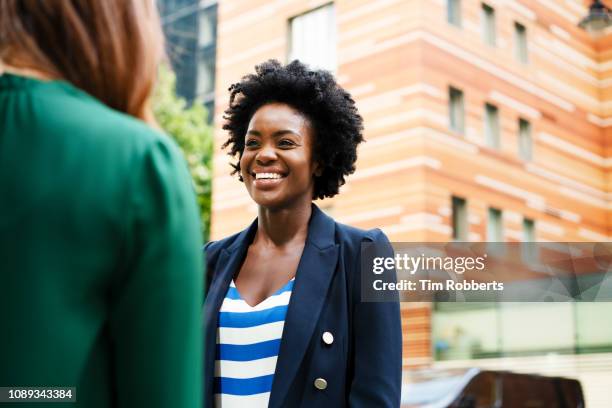 two women having business discussion, smiling - business in the city stock-fotos und bilder