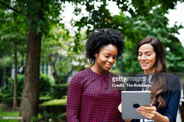 two women with tablet - summer women talking stockfoto's en -beelden