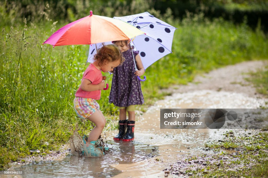 Jeunes filles tenant des parapluies et jouant dans l’eau