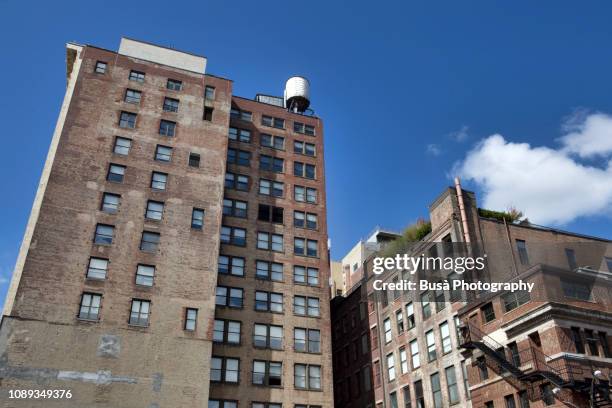 water tower on top of tall old building in lafayette street, noho, manhattan, new york city, usa - nyc building sun ストックフォトと画像