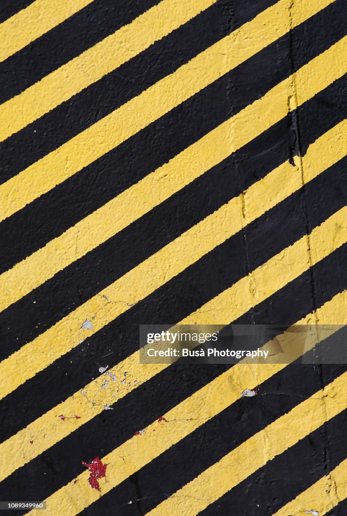 Concrete wall painted with yellow and black stripes, usually used in construction sites with the meaning: do not enter the area / caution