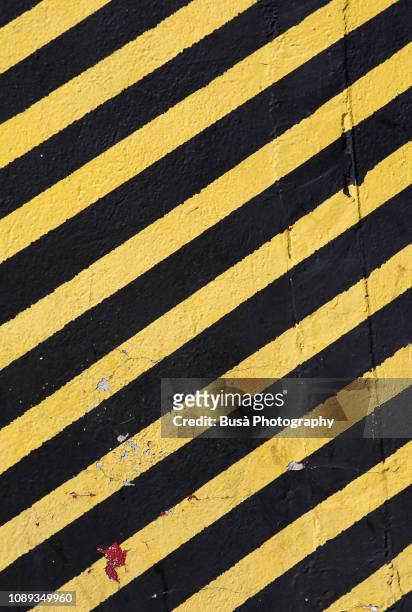 concrete wall painted with yellow and black stripes, usually used in construction sites with the meaning: do not enter the area / caution - construction danger stock pictures, royalty-free photos & images