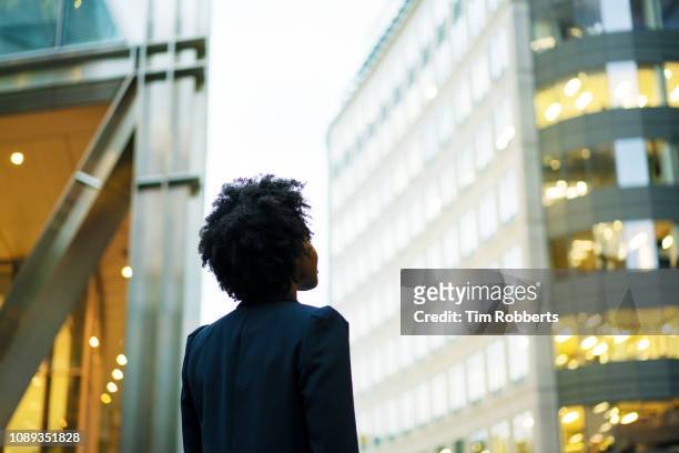 woman looking up at office buildings - attesa foto e immagini stock