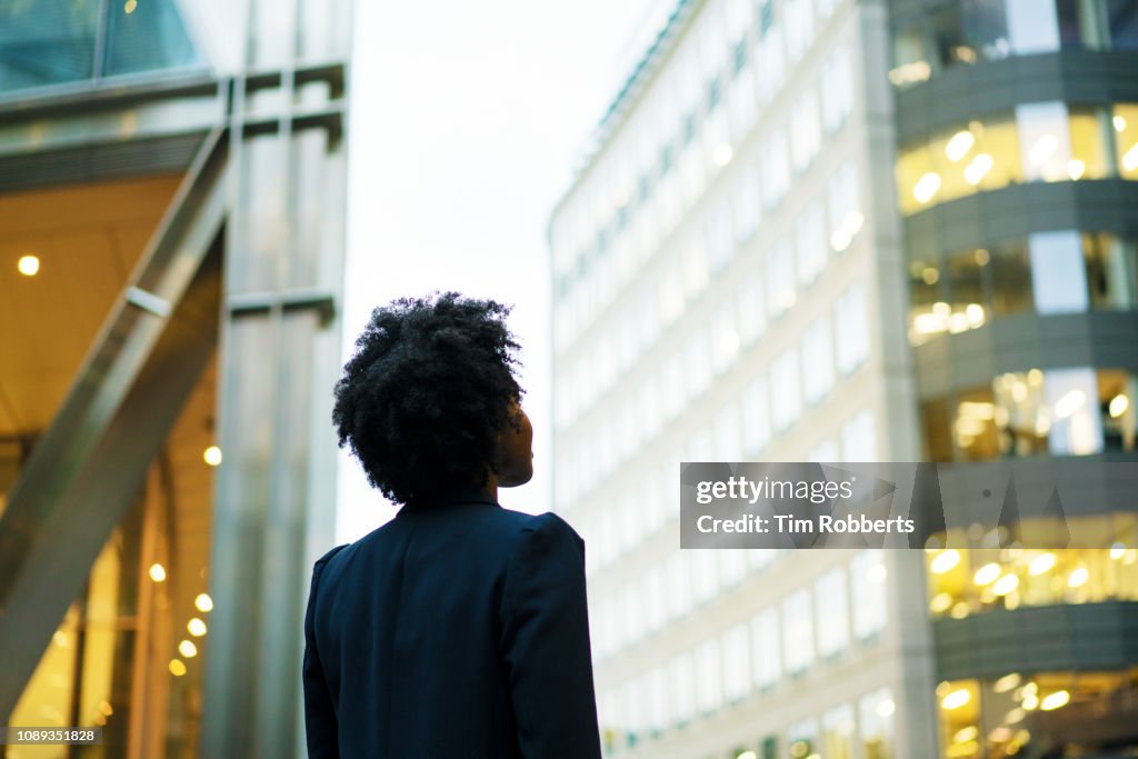 Woman looking up at office buildings