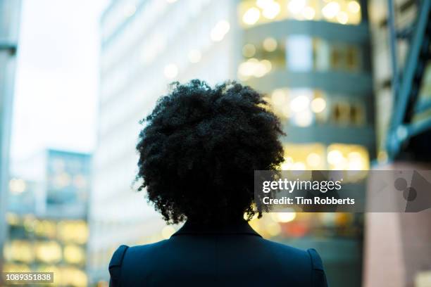 woman looking up with office buildings. - afro back stock pictures, royalty-free photos & images