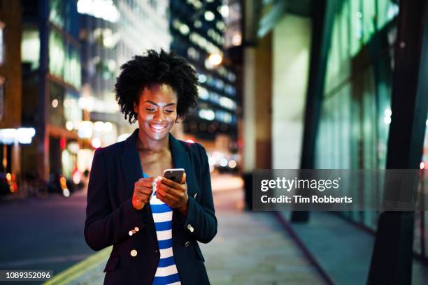 woman using smart phone at night, smiling - city of london stockfoto's en -beelden