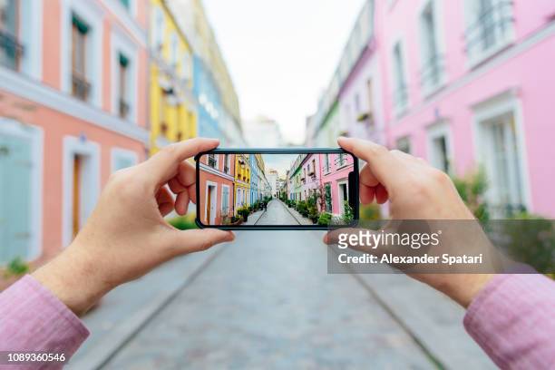 personal perspective of a man photographing colorful street rue cremieux with smartphone, paris, france - smartphone pov stockfoto's en -beelden