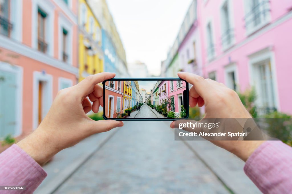 Personal perspective of a man photographing colorful street Rue Cremieux with smartphone, Paris, France