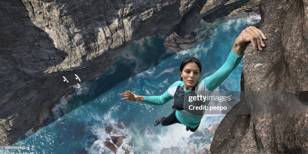 Free Climber Hangs One Handed On Sea Cliff Rock Face