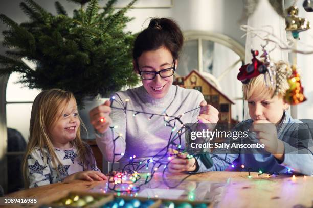 woman and children decorating for christmas - untangle stockfoto's en -beelden